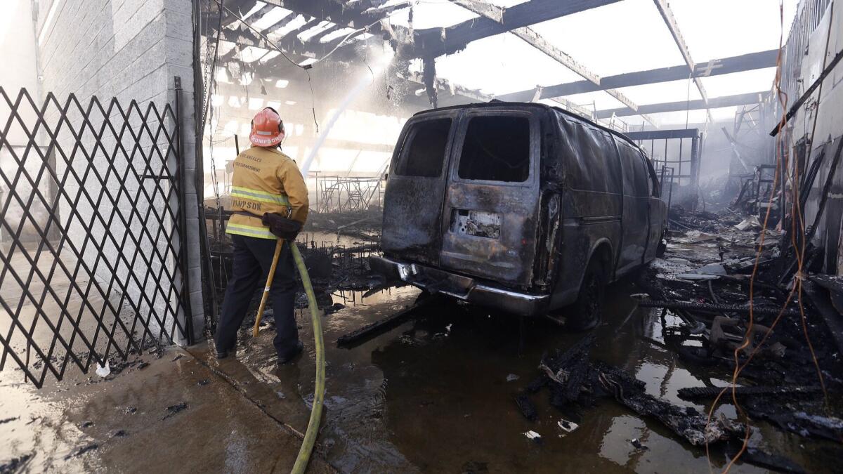 LAFD Capt. Eric Thompson douses hot spots after a fire at the Priceless clothing company in the the 700 block of East Pico Boulevard in downtown Los Angeles.