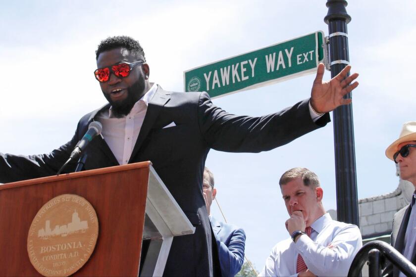 FILE - In this June 22, 2017 file photo, retired Boston Red Sox designated hitter David Ortiz is honored with the renaming of a portion of Yawkey Way to David Ortiz Drive outside Fenway Park in Boston. Red Sox principal owner John Henry, at right, says he wants to take steps to rename all of Yawkey Way, a street that has been an enduring reminder of the franchise's complicated racial past. At center rear is Boston Mayor Marty Walsh. (AP Photo/Charles Krupa, File)