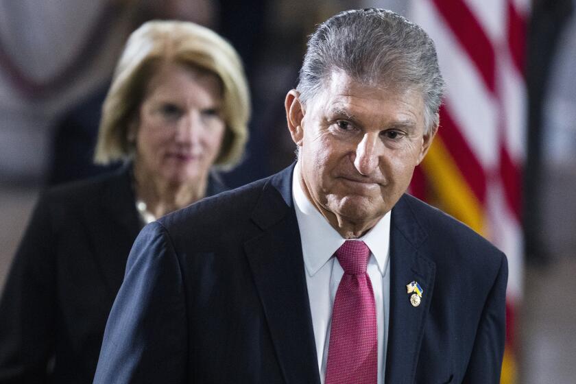 Sen. Joe Manchin, D-W.Va., and Sen. Shelley Moore Capito, R-W.Va., pay their respects as the flag-draped casket bearing the remains of Hershel W. "Woody" Williams, lies in honor in the U.S. Capitol, Thursday, July 14, 2022 in Washington. Manchin has told Senate Majority Leader Chuck Schumer that he will oppose a economic measure if it includes climate or energy provisions or boosts taxes on the rich or corporations. (Tom Williams/Pool photo via AP)