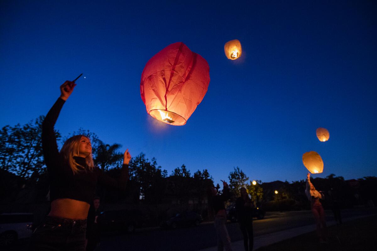 Madison Moore launches a paper lantern into the night during a surprise 16th-birthday celebration for her Tuesday in Huntington Beach.