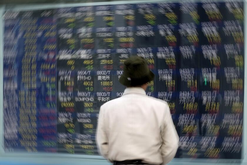 A pedestrian pauses in front of an electronic board at the Tokyo Stock Exchange on Tuesday.