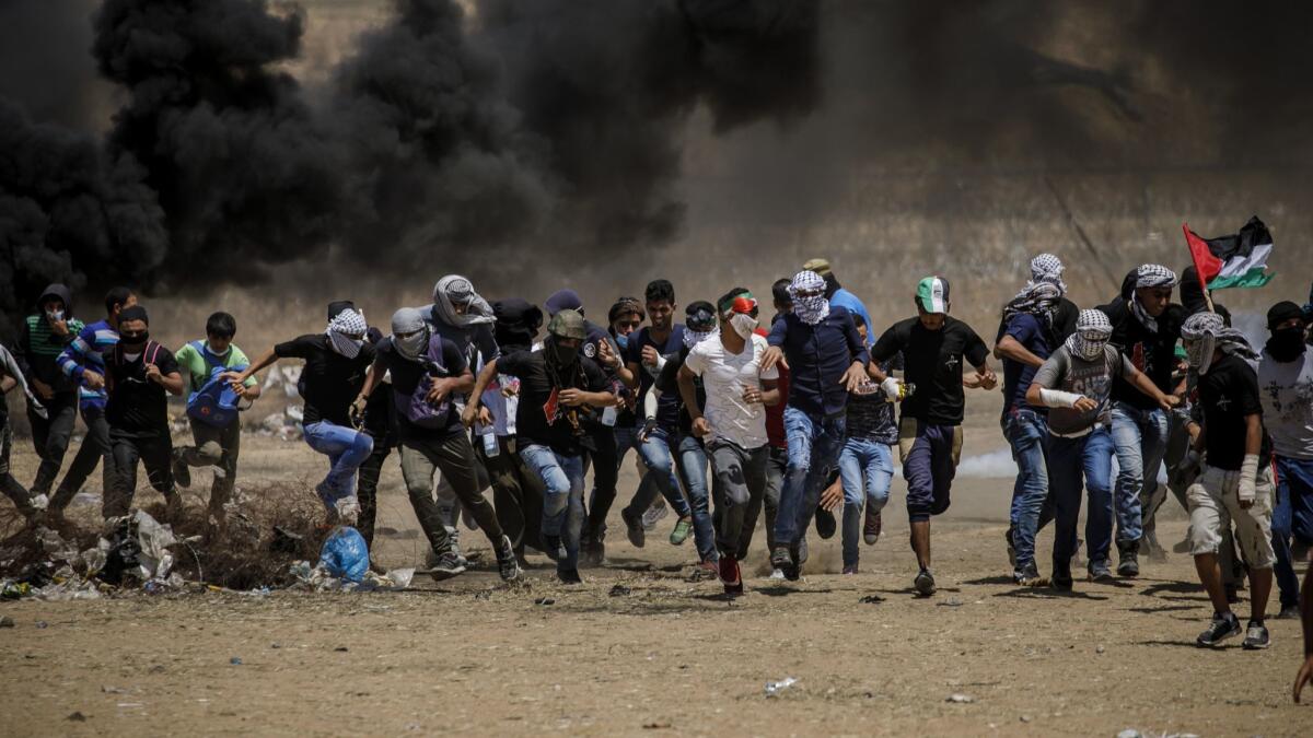 Palestinian protesters flee tear gas on Friday at the border fence separating Israel and the Gaza Strip.