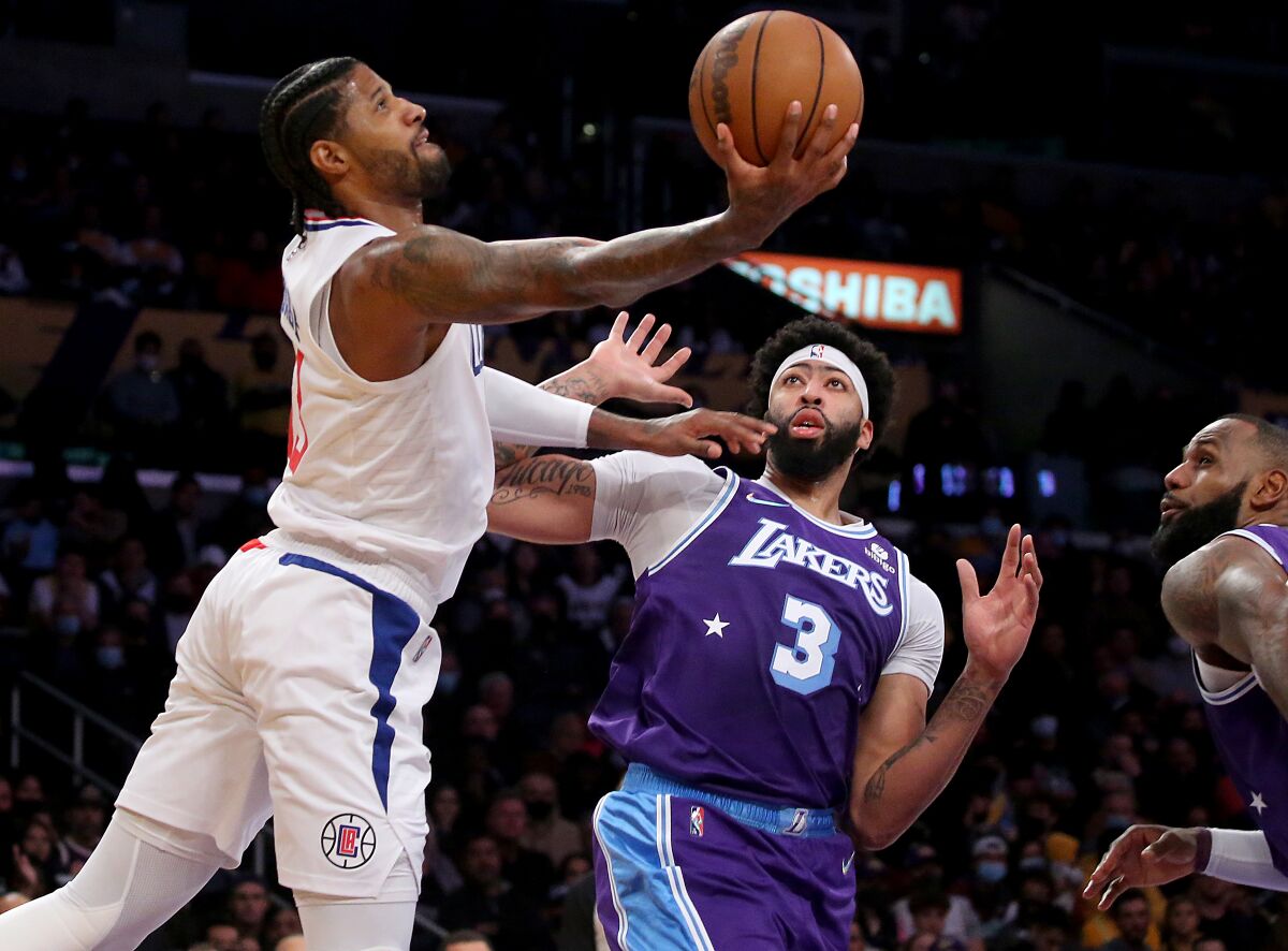 Clippers forward Paul George elevates past Lakers stars Anthony Davis and LeBron James for a layup.