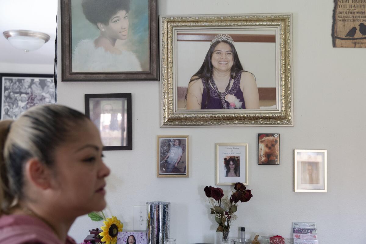 Ena Palma, left, speaks of memories with her sister, Yanet Palma-Perez, who is pictured on the wall in her Wilmington, Calif., home. Yanet Palma-Perez died at the hands of her husband in 2016.