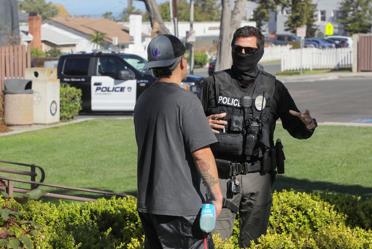 Carlsbad police Officer Chris Collier, a member of the department's Homeless Outreach Team, speaks with Ronnie Quick.