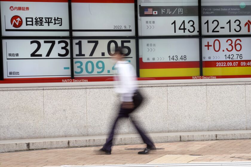 FILE - A person walks past an electronic stock board showing Japan's Nikkei 225 index and U.S. dollar/Japanese yen exchange rate at a securities firm in Tokyo on Sept. 7, 2022. Business sentiment among large manufacturers worsened for the third straight quarter, a Bank of Japan survey showed Monday, Oct. 3, 2022, as the nation grappled with rising costs, the dropping value of the yen and restrictions on economic activity over the coronavirus pandemic. (AP Photo/Eugene Hoshiko, File)