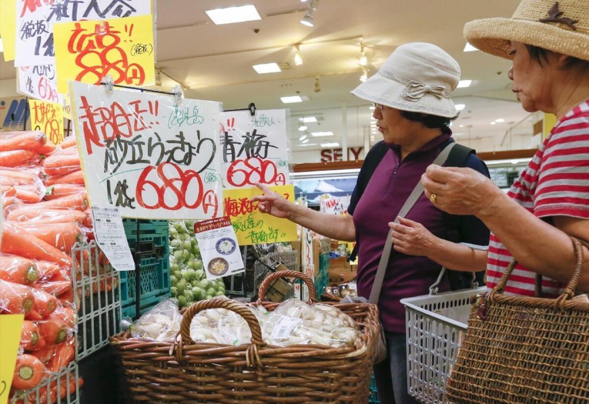 Falling palm oil prices in Southeast Asia, increased soybean crushing for oil in South America and rising dairy supplies contributed to an ease in global food prices. Above, Japanese shoppers compare produce prices in Tokyo last week.