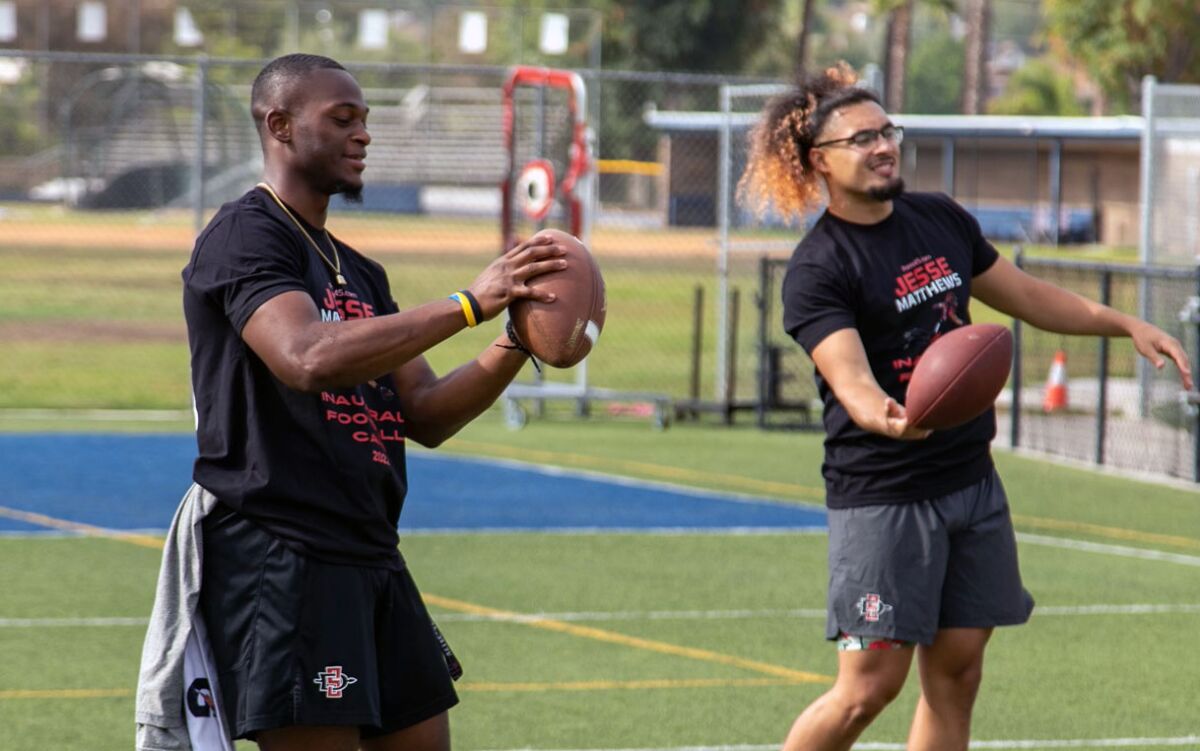 San Diego State wide receiver TJ Sullivan (left) and linebacker Michael Shawcroft toss football around with campers.