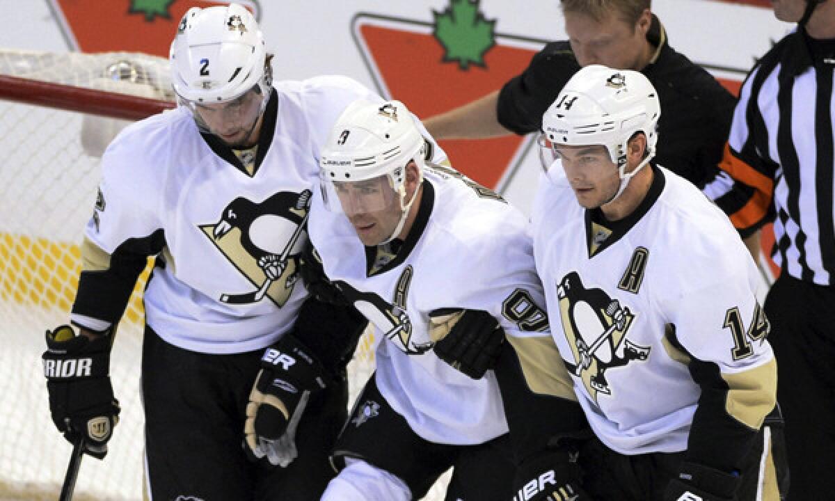 Pittsburgh Penguins forward Pascal Dupuis, center, is helped off the ice by teammates Matt Niskanen, left, and Chris Kunitz after suffering a torn anterior cruciate ligament against the Ottawa Senators on Dec. 23. Despite being plagued by injuries, the Penguins are winning games.
