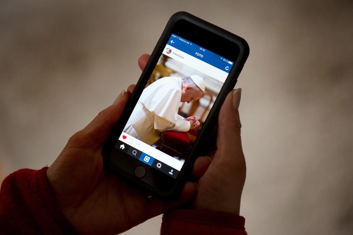 Una mujer sostiene un smartphone que muestra la cuenta de Instagram del Papa Francisco.