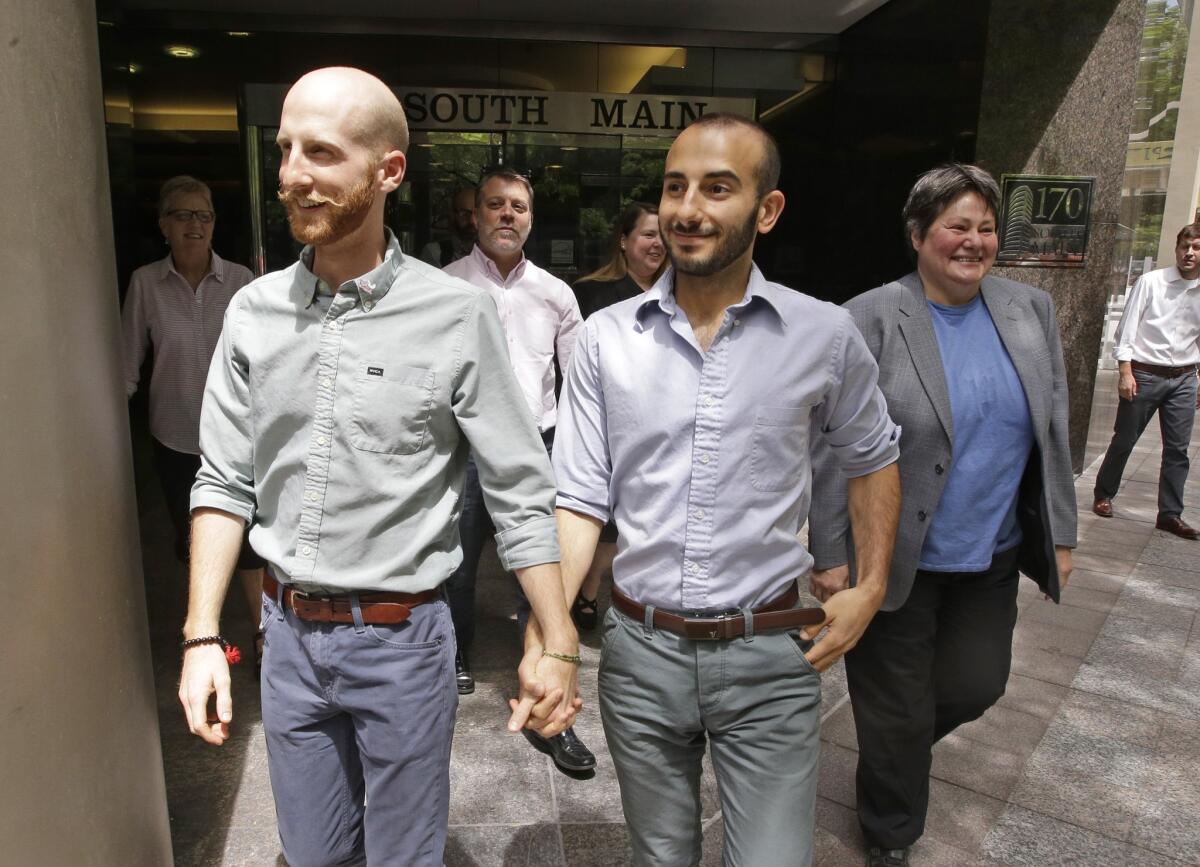 Plaintiffs Moudi Sbeity, right, and his partner Derek Kitchen, one of two couples who brought the lawsuit against the Utah's gay marriage ban, walk with fellow plaintiff Kate Call as they arrive for a news conference in Salt Lake City.