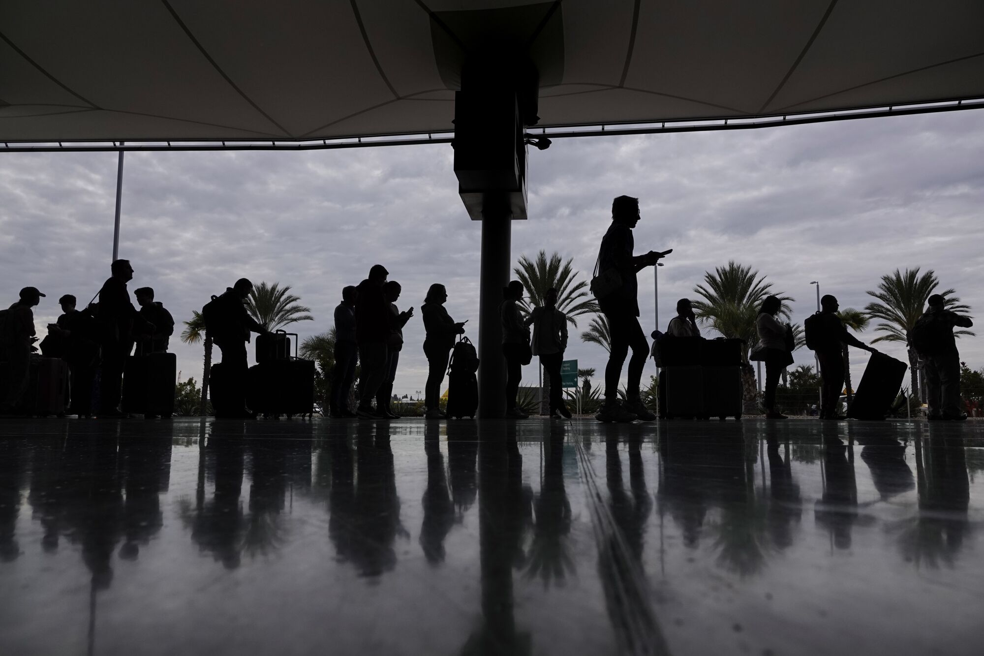People wait in line to rent a car at the rental car center at the San Diego International Airport on Tuesday. 