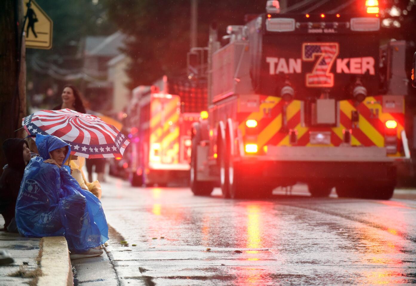 Spectators try to stay dry as they watch the parade from the safety of umbrellas and ponchos during the Manchester Volunteer Fire Company carnvial on Tuesday, July 2.