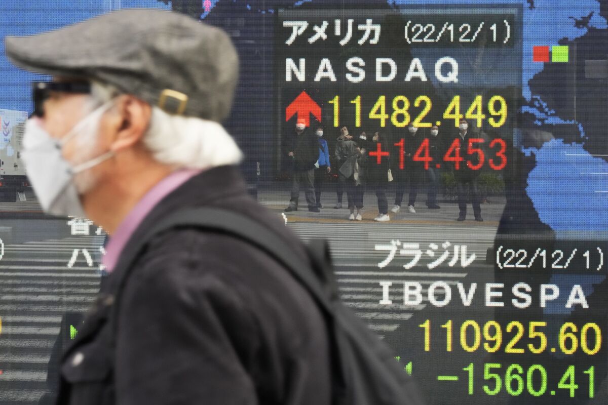 Pedestrians are seen reflected on monitors showing the U.S. NASDAQ and other countries' stock market indexes at a securities firm in Tokyo, Friday, Dec. 2, 2022. Shares retreated in Asia on Friday after a mixed day on Wall Street as optimism over signs the Federal Reserve may temper its aggressive interest rate hikes was replaced by worries the economy might be headed for a recession. (AP Photo/Hiro Komae)