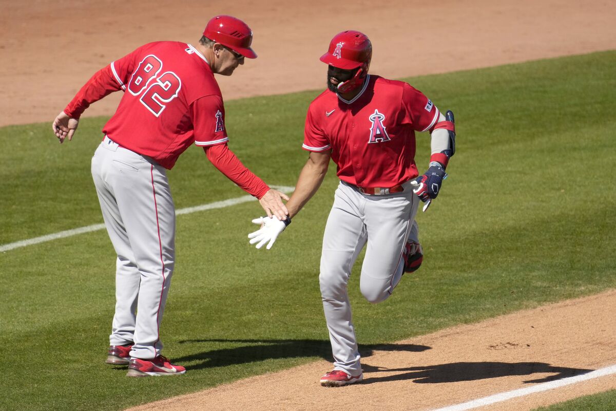 Jo Adell, right, celebrates with third base coach Bill Haselman (82) after hitting a two-run home run.