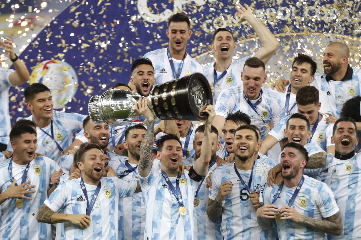 Argentina's Lionel Messi holds the trophy as he celebrates with teammates 