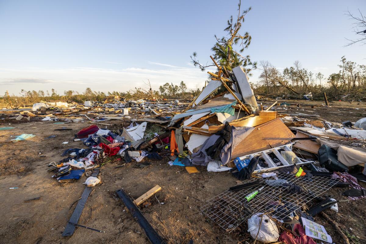 A home lies crumpled with clothing and debris strewn around it. 