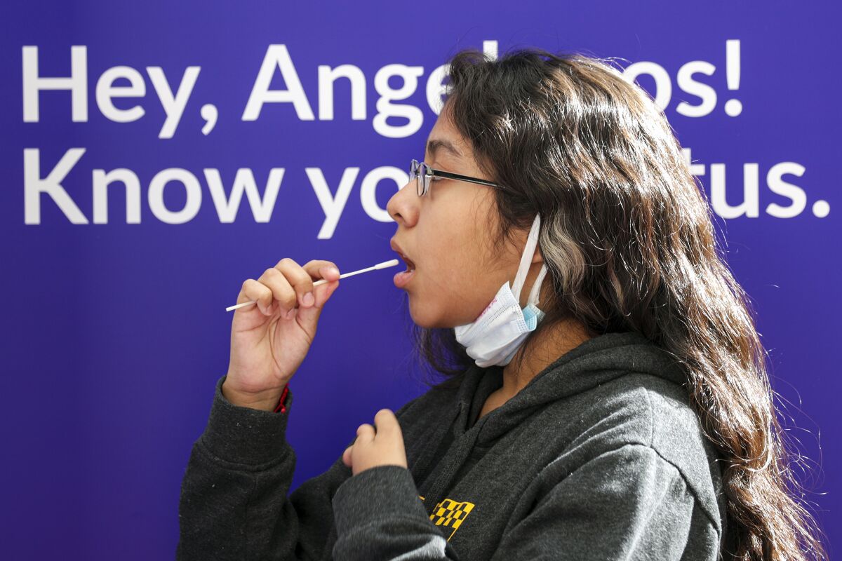 A girl swabs the inside of her mouth for a coronavirus test