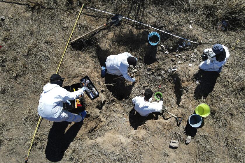 Forensic technicians excavate a field on a plot of land referred to as a cartel "extermination site" where burned human remains are buried, on the outskirts of Nuevo Laredo, Mexico, Tuesday, Feb. 8, 2022. The insufficiency of investigations into Mexico’s nearly 100,000 disappearances is evident. There are 52,000 unidentified people in morgues and cemeteries, not counting places like this one, where the charred remains are measured only by weight. (AP Photo/Marco Ugarte)