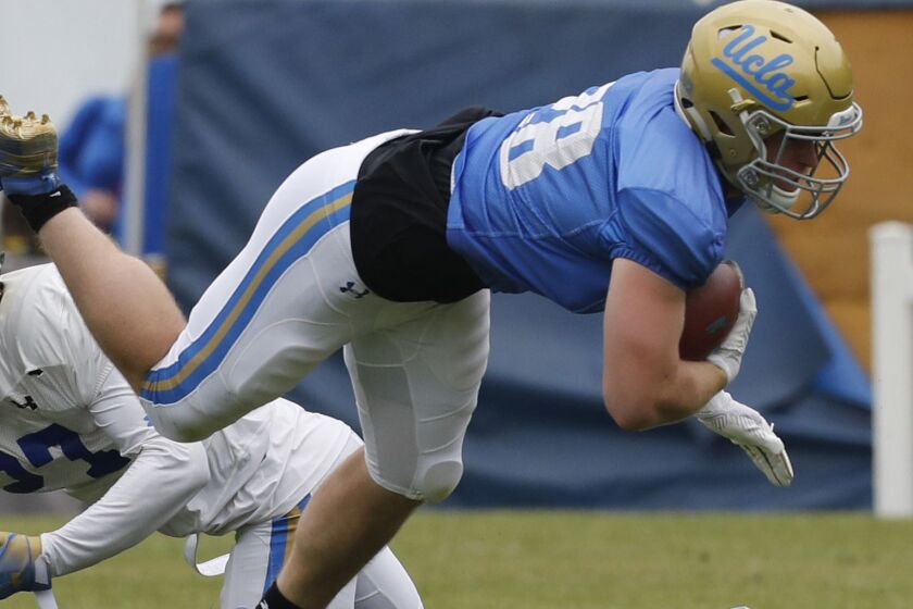 LOS ANGELES, CALIF. - APRIL 20, 2019. UCLA running back Cole Kinder gets tripped up by Patrick Jolly during the annual spring intrasquad football game at Drake Stadium in Westwood on Saturday, April 20, 2019. (Luis Sinco/Los Angeles Times)