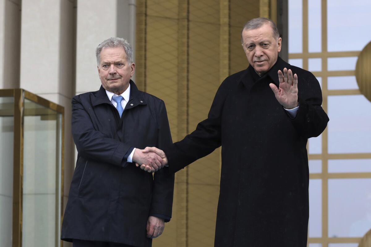 Finnish President Sauli Niinisto and Turkish President Recep Tayyip Erdogan shaking hands in front of a building