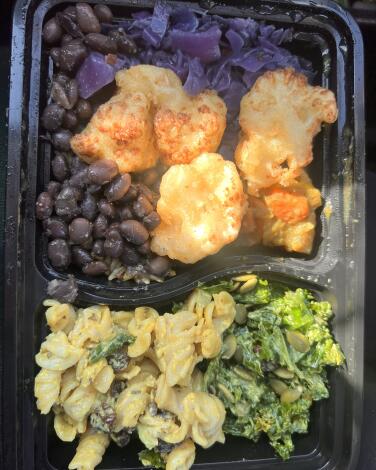 A plate with fried cauliflower, purple cabbage, black beans, rice, kale and macaroni salad.
