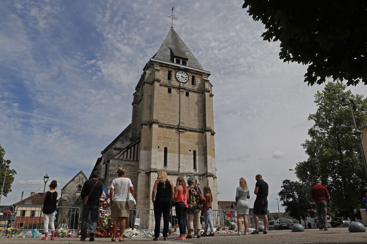 Residents gather at a makeshift memorial in front of the church where priest Jacques Hamel was killed July 26 in St.-Etienne-du-Rouvray, France.