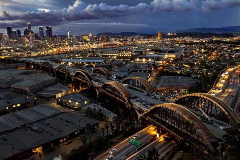 LOS ANGELES, CA - April 15: An aerial view of a dramatic sky over the Los Angeles skyline as progress is underway on the Sixth Street Viaduct Replacement Project that crosses the 101 Freeway and Los Angeles River in Los Angeles. The bridge is an on-going $588 million bridge replacement project, consisting of 10 sets of arches, which will be LED-lit, forming the "Ribbon of Light'' along the viaduct. The project is funded by the Federal Highway Administration, State, and City and scheduled for completion in Summer of 2022. Photo taken on Thursday, April 15, 2021 in Los Angeles, CA. The arches are 10 feet wide, with a typical arch span of 300 feet. Each arch takes 260 cubic yards of concrete to construct or about 65 trucks of concrete. In order to keep the concrete cool enough, it is delivered to the site, then injected with liquid nitrogen to keep it close to ambient temperature. This reduces the potential for concrete cracking. (Allen J. Schaben / Los Angeles Times)