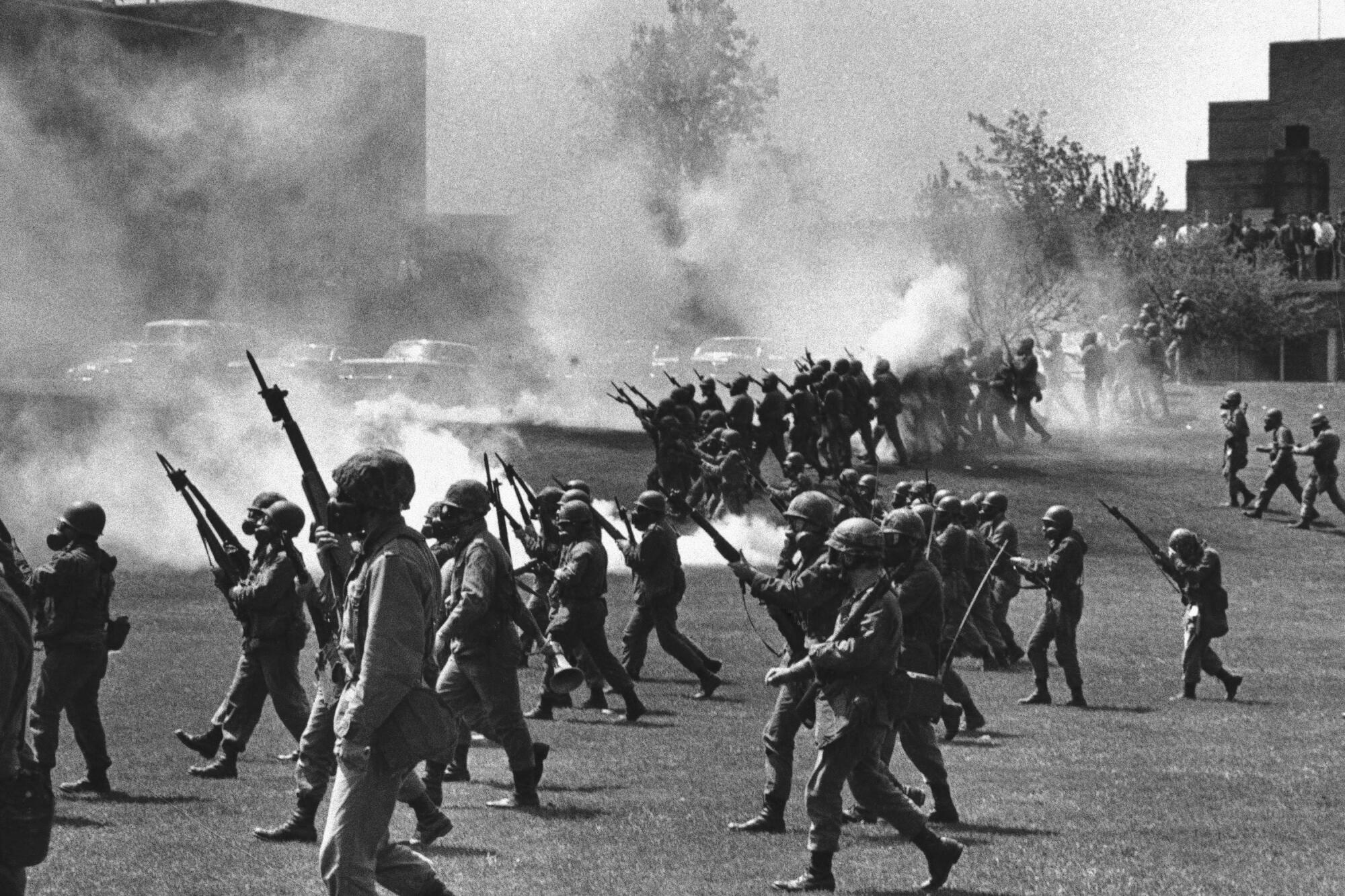 National Guardsmen advancing over a grassy area 