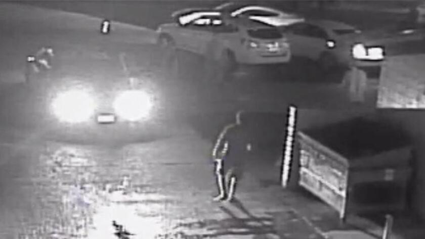 A still frame from surveillance video released by the District Attorney's Office in 2015 shows an alley in the Midway District with a police car's headlights shining on Fridoon Nehad (next to dumpster). Nehad was shot and killed by a police officer a moment later.