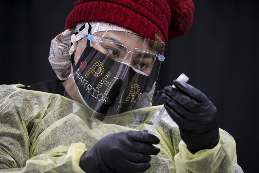 Ontario, CA - February 04: Crystal Martin, an RN, prepares first dose of Pfizer-BioNTech COVID-19 vaccine at a vaccination site started by San Bernardino County Department of Public Heath at Ontario Convention Center on Thursday, Feb. 4, 2021 in Ontario, CA.(Irfan Khan / Los Angeles Times)