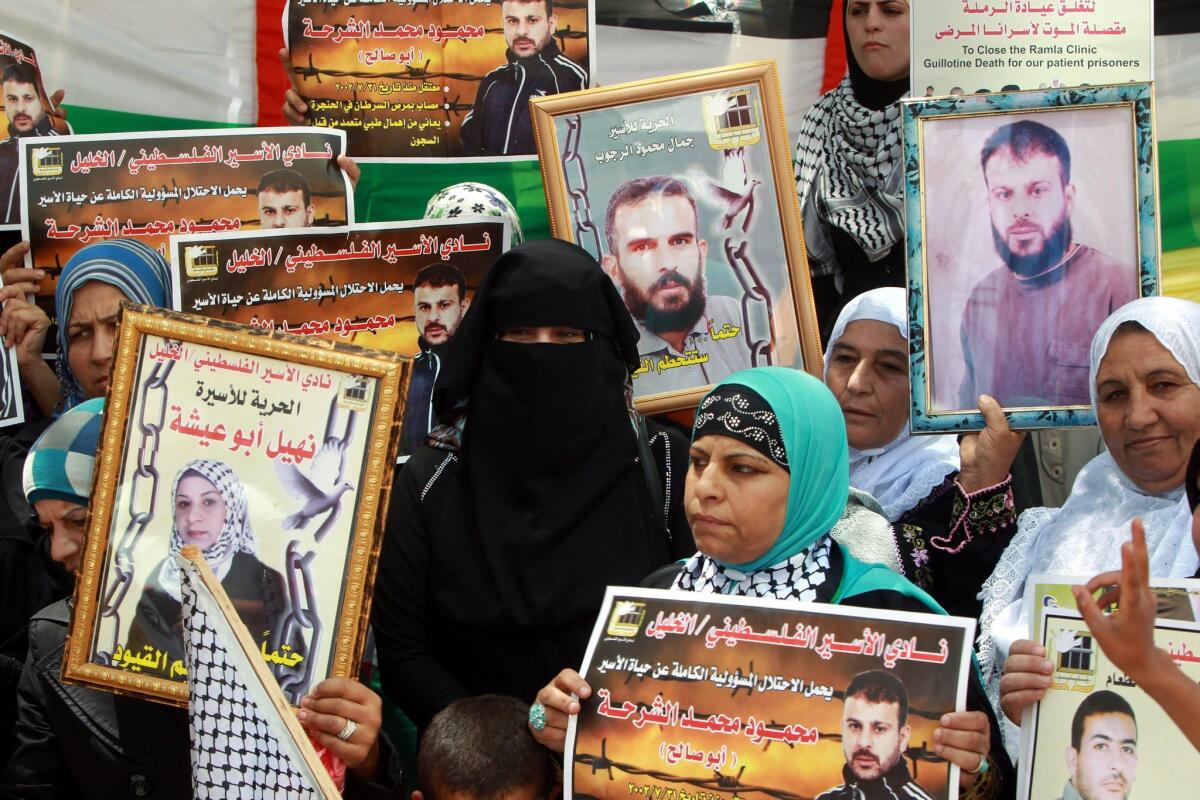 Palestinians hold pictures during a rally on July 8 to show solidarity with Palestinian prisoners in the West Bank city of Hebron. A top Israeli official said Saturday that Israel was willing to release some "hardcore" prisoners as part of a U.S.-backed peace initiative.