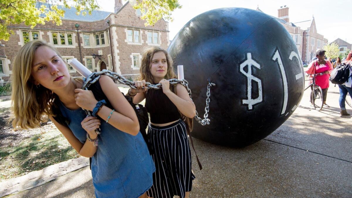 Students pull a ball-and-chain prop, representing student debt, at Washington University in St. Louis in 2016.