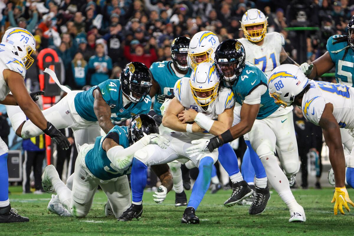 Jaguars defenders smother Chargers quarterback Justin Herbert late in the AFC wild-card game.