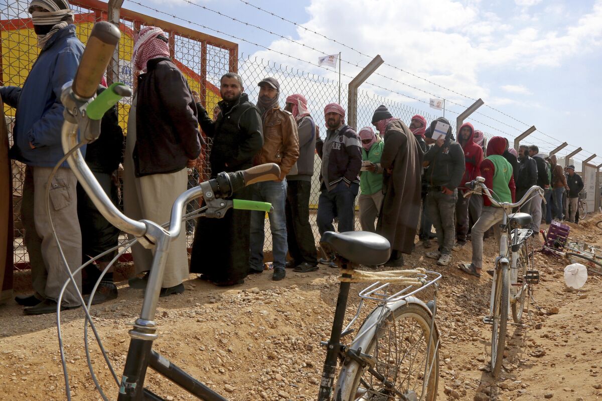 FILE - In this Feb. 18, 2018 file photo, Syrian refugees line up to register their names at an employment office, at the Azraq Refugee Camp, 100 kilometers (62 miles) east of Amman, Jordan. The U.N. agency for refugees said Tuesday, Sept. 8, 2020, that it has confirmed two coronavirus cases in the Azraq camp. They are the first infections to be detected among Syrians living in refugee camps in Jordan, which are home to more than 100,000 Syrians displaced by that country's civil war. (AP Photo/Raad Adayleh, File)