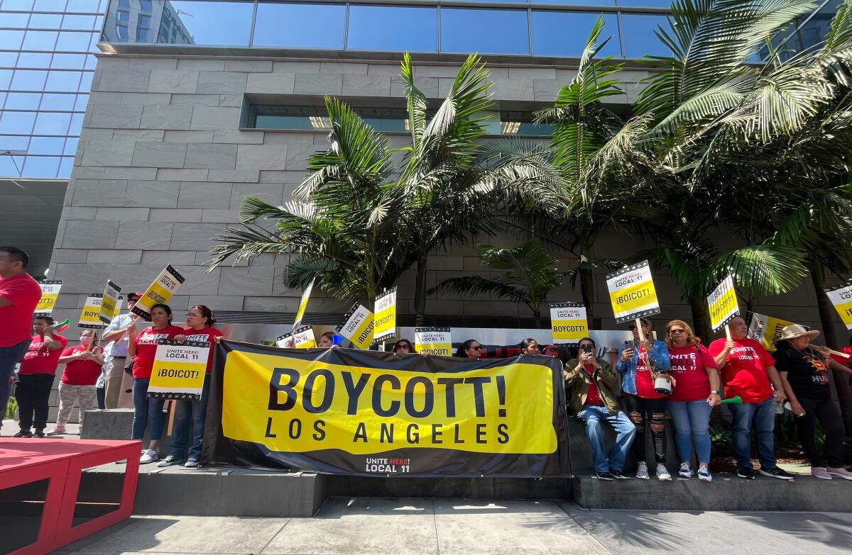 Hotel workers carry a large yellow banner reading "Boycott"