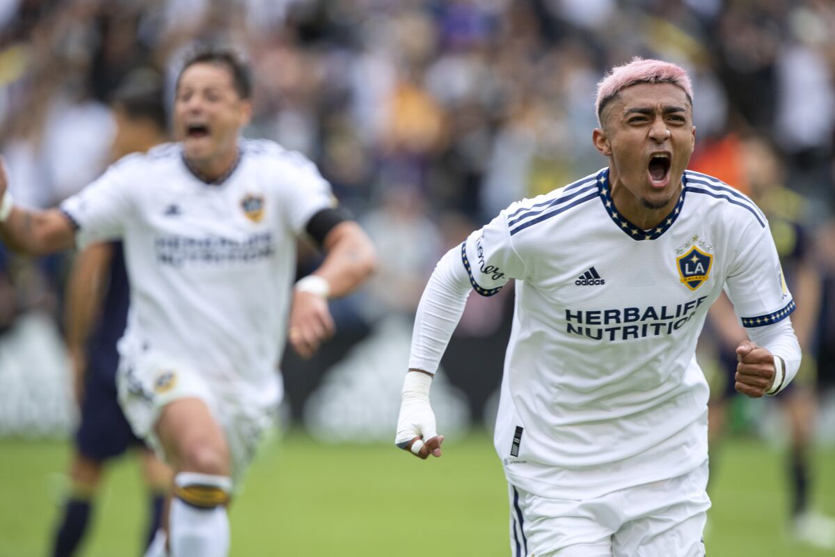 Galaxy defender Julian Araujo, right, reacts after scoring a goal, with forward Javier Hernandez following.