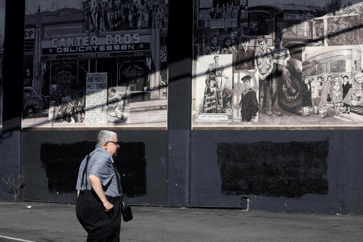 A man walks past the wall of the parking lot at Canter's Deli.