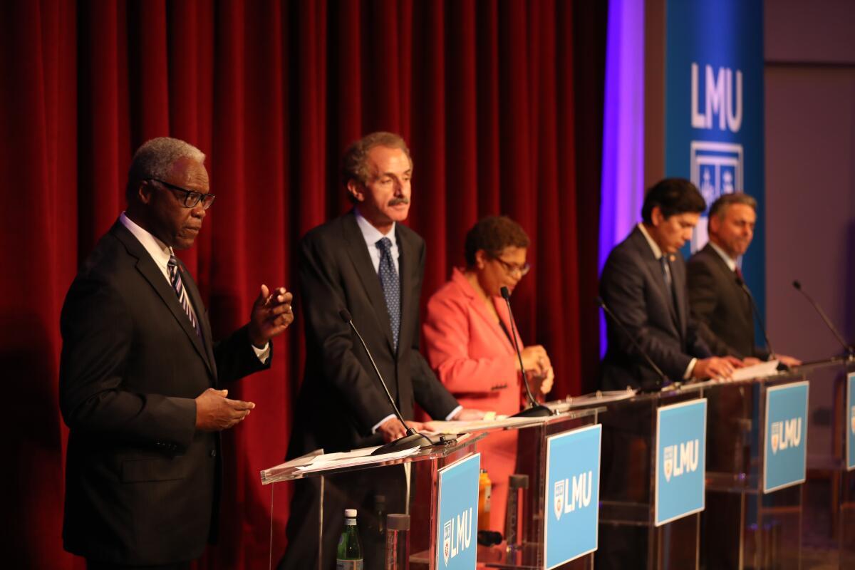 Standing behind lecterns on debate stage are, from left, Mel Wilson, Mike Feuer, Karen Bass, Kevin de León and Joe Buscaino.