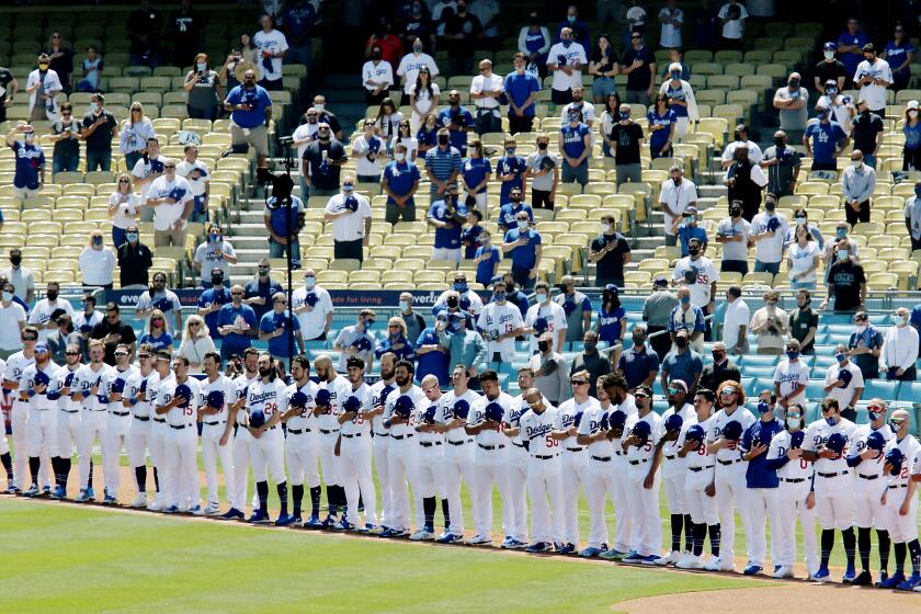 The Dodgers and fans stand for the national anthem for the home opener April 9, 2021, at Dodger Stadium.