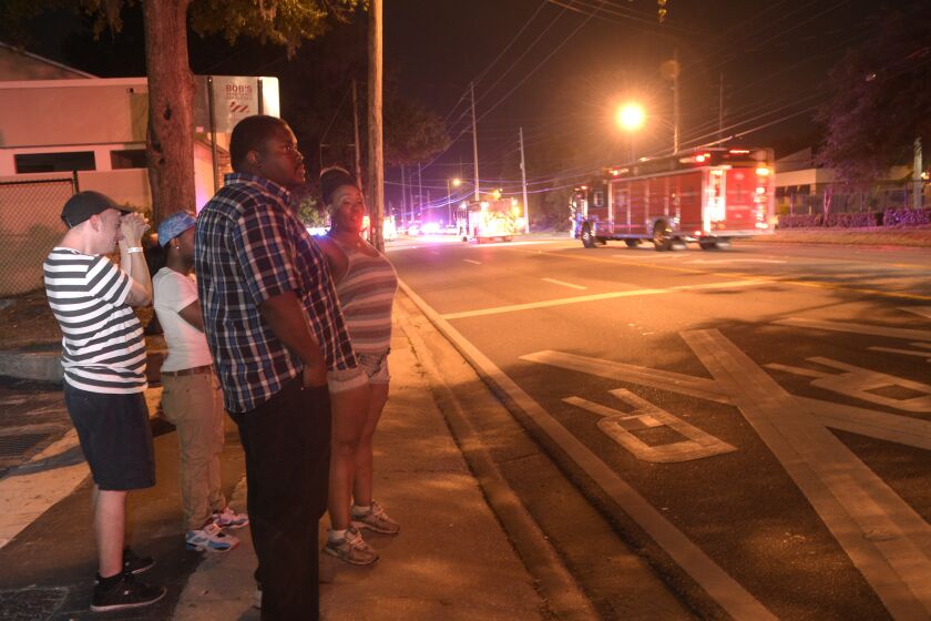 Bystanders wait down the street from a shooting involving multiple fatalities at the Pulse nightclub in Orlando, Fla. on June 12.