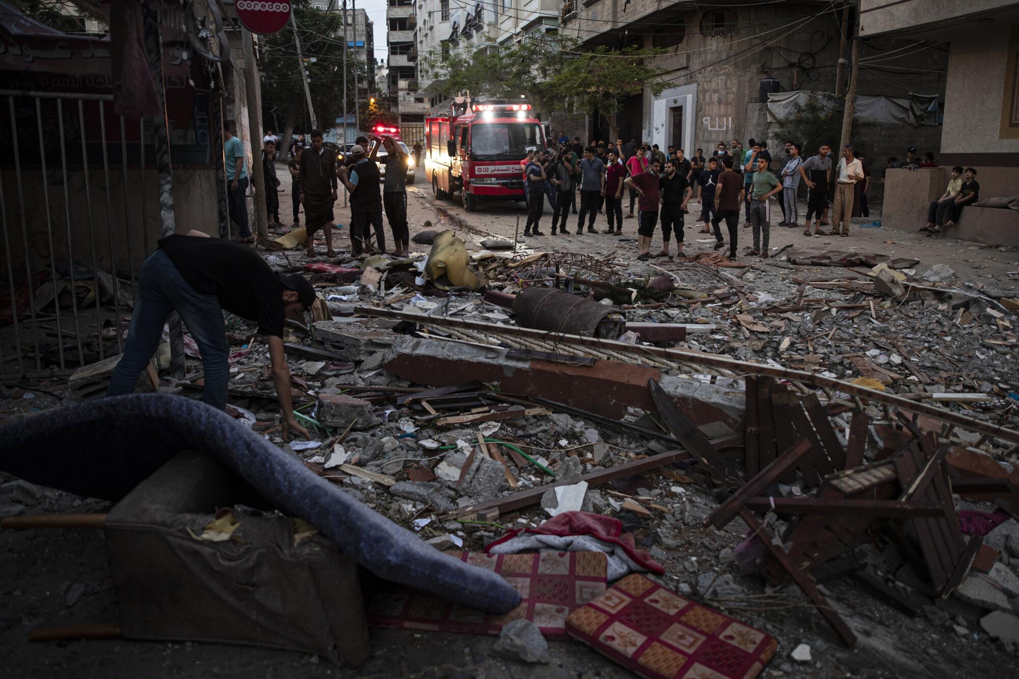 A man bends down to pick up something from the debris-strewn ground 