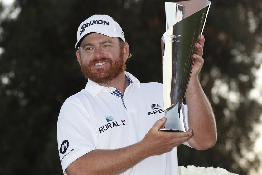 J.B. Holmes holds the winner's trophy on the 18th green after the conclusion of the Genesis Open golf tournament at Riviera Country Club.