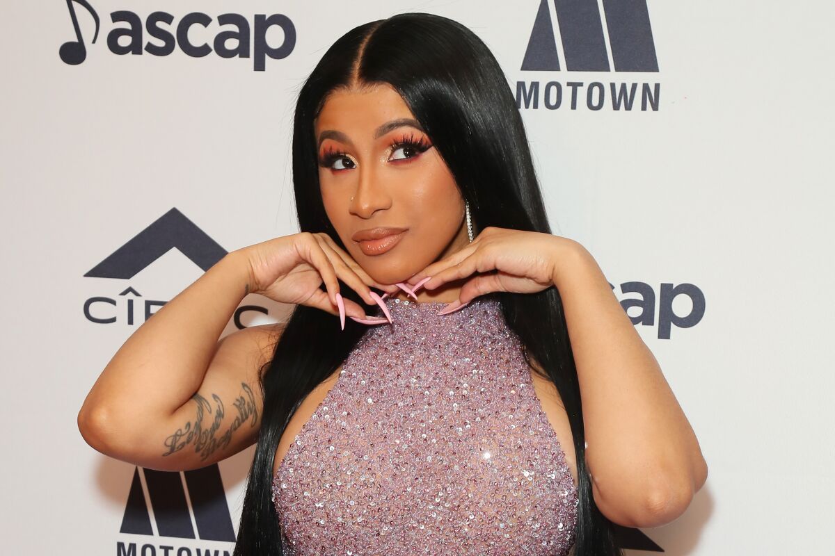 Cardi B poses coyly with her hands under her chin