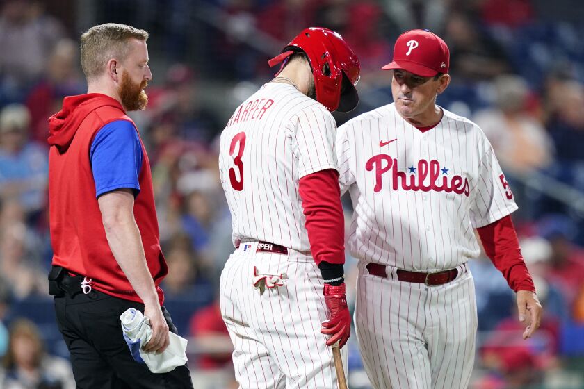 Philadelphia Phillies' Bryce Harper, center, is checked on by interim manager Rob Thomson, right, during the sixth inning of a baseball game against the Miami Marlins, Wednesday, Sept. 7, 2022, in Philadelphia. (AP Photo/Matt Slocum)