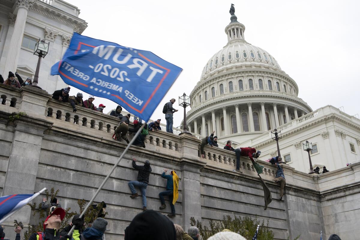 Violentos partidarios del presidente Donald Trump escalando el muro del Capitolio en Washington.