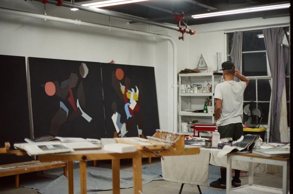 man in a studio with large-scale paintings