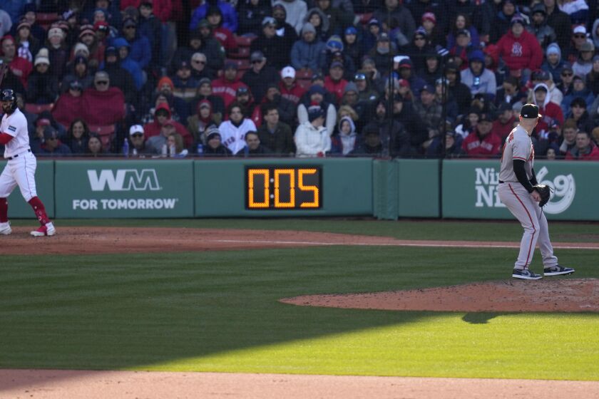 Baltimore Orioles relief pitcher Logan Gillaspie, right, starts to deliver a pitch to Boston Red Sox's Connor Wong, as the pitch clock ticks to five seconds, during the eighth inning of an opening day baseball game at Fenway Park, Thursday, March 30, 2023, in Boston. (AP Photo/Charles Krupa)