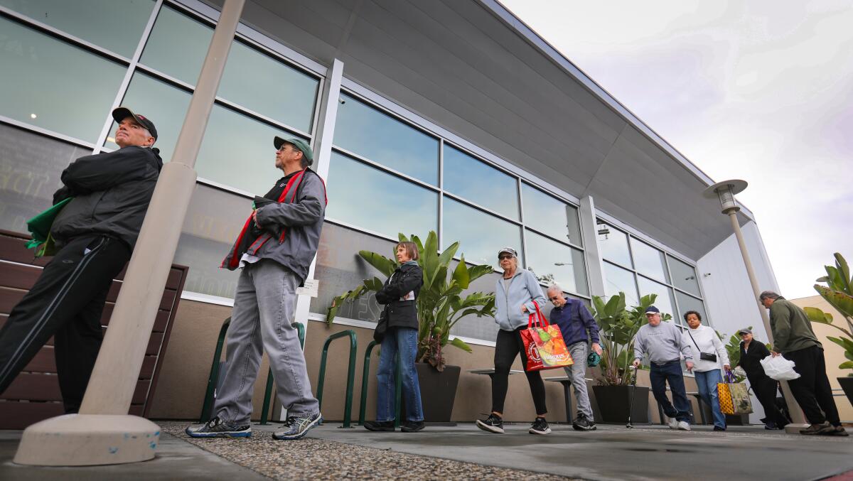 Los compradores mayores esperan en fila afuera de Barons Market en North Park para que la tienda abra, sólo para mayores, una hora antes de que el mercado abra al público en general el 20 de marzo de 2020 en San Diego.