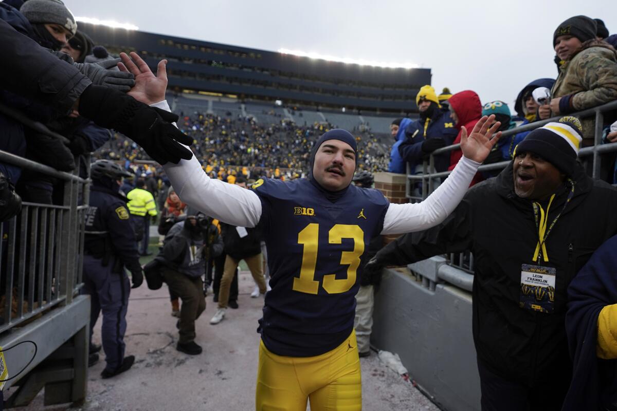 Michigan kicker Jake Moody slaps hands with fans as he exits the field Saturday.